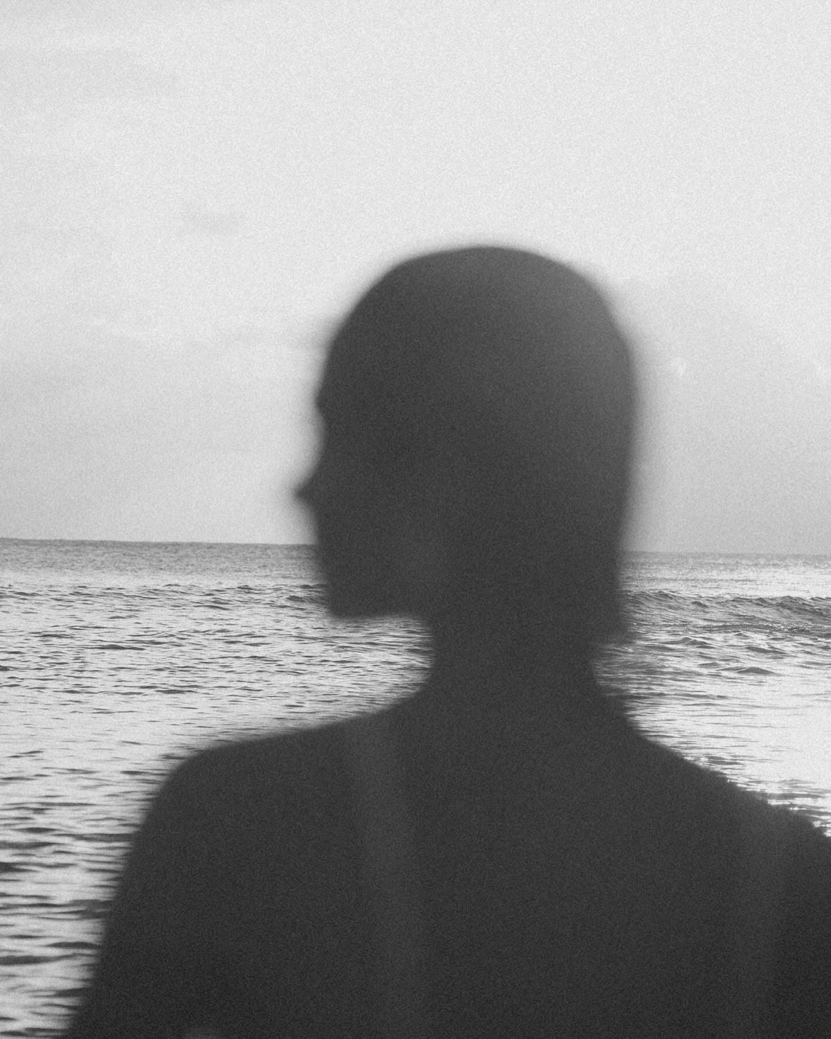 Black-and-white silhouette of a woman facing the sea