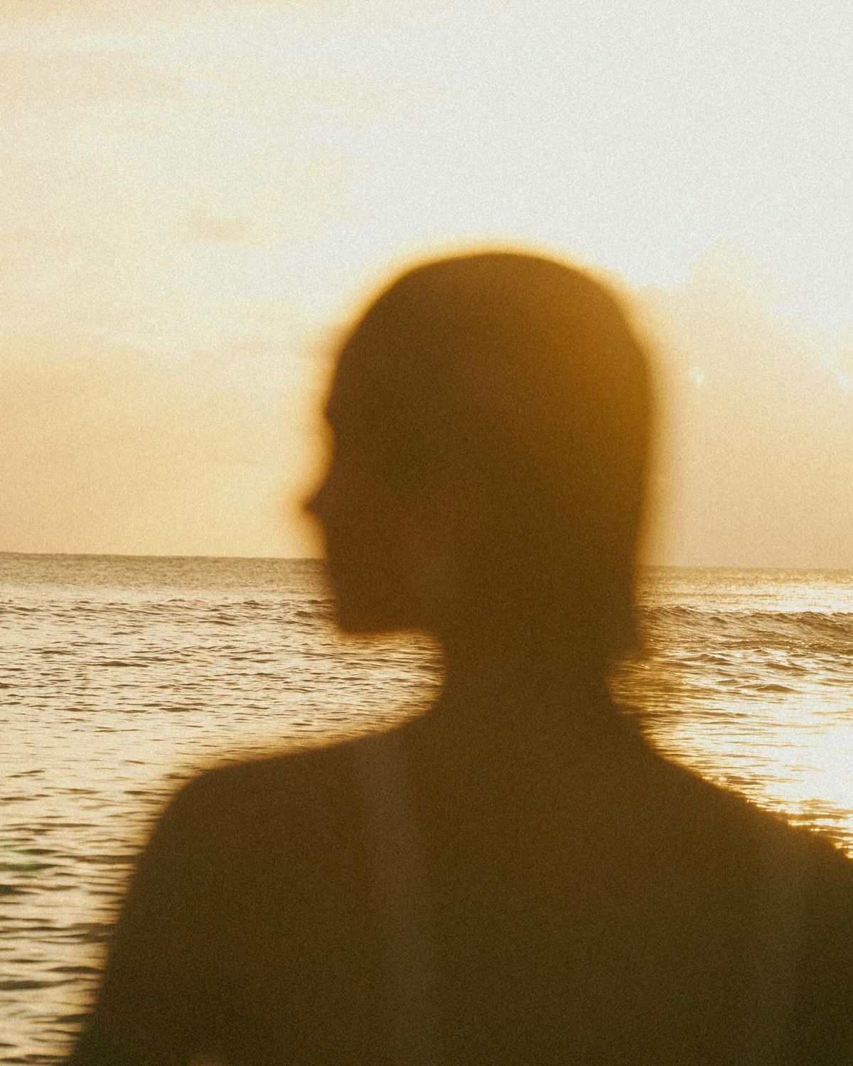 Silhouette of a woman against the sea at golden hour